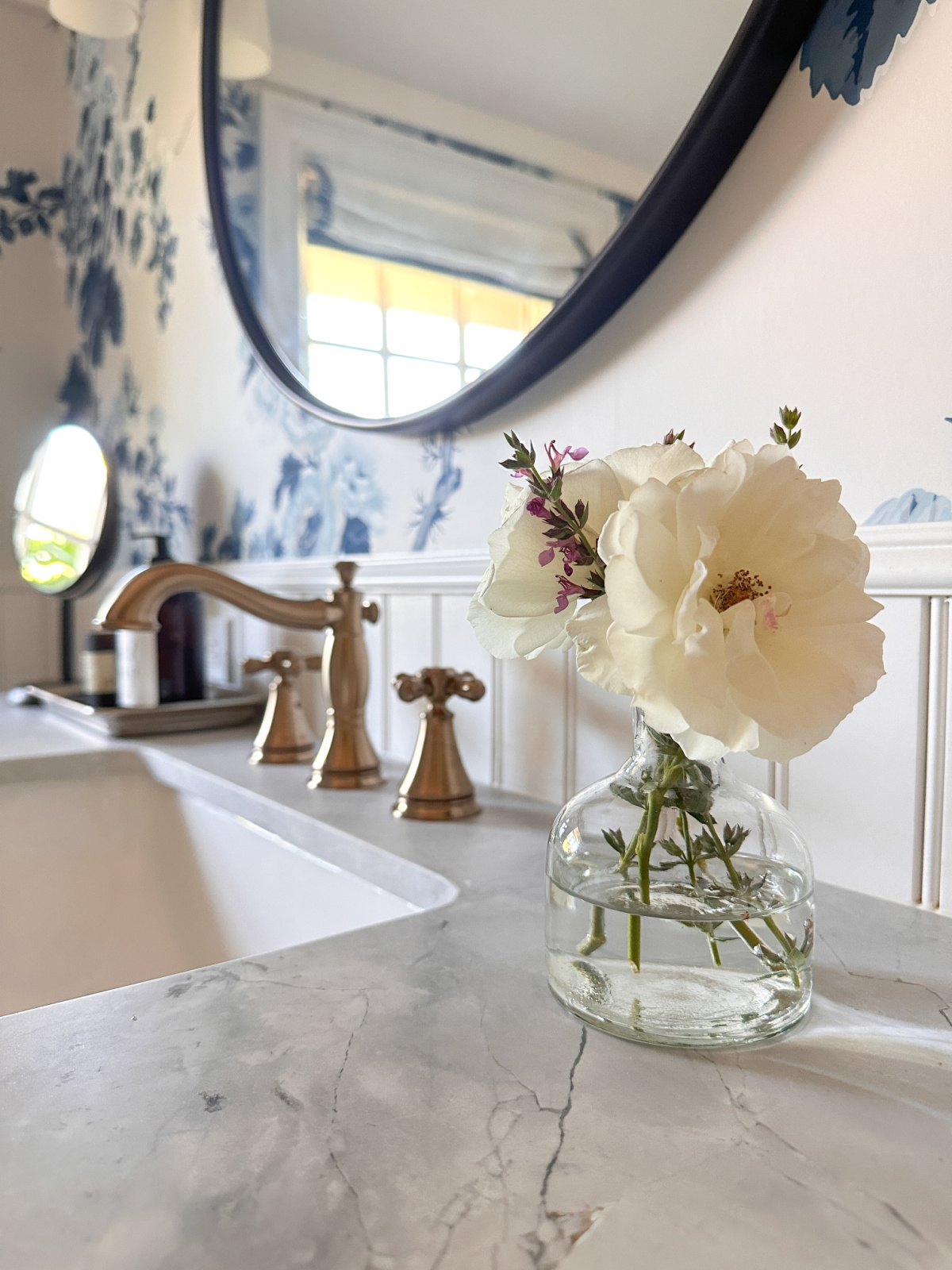 Bud vase of roses and lavender on bathroom counter.