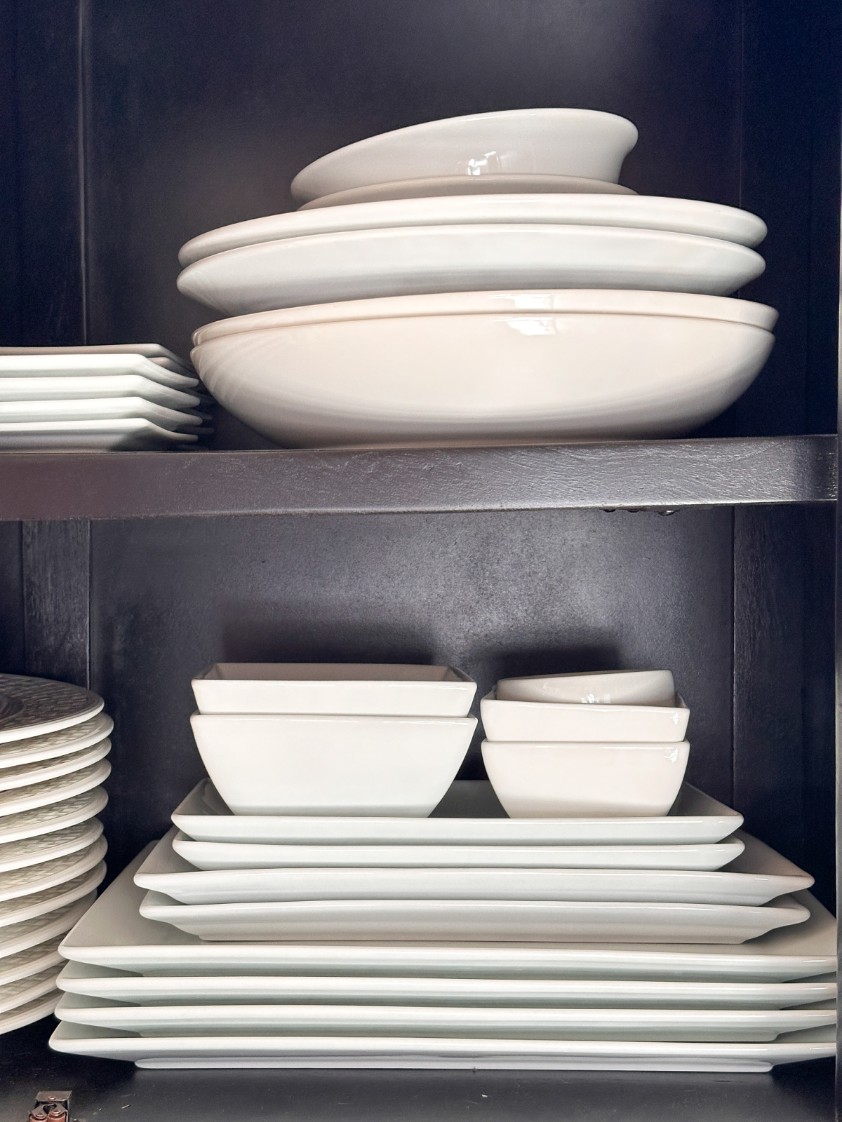 White platters and bowls in cupboard.