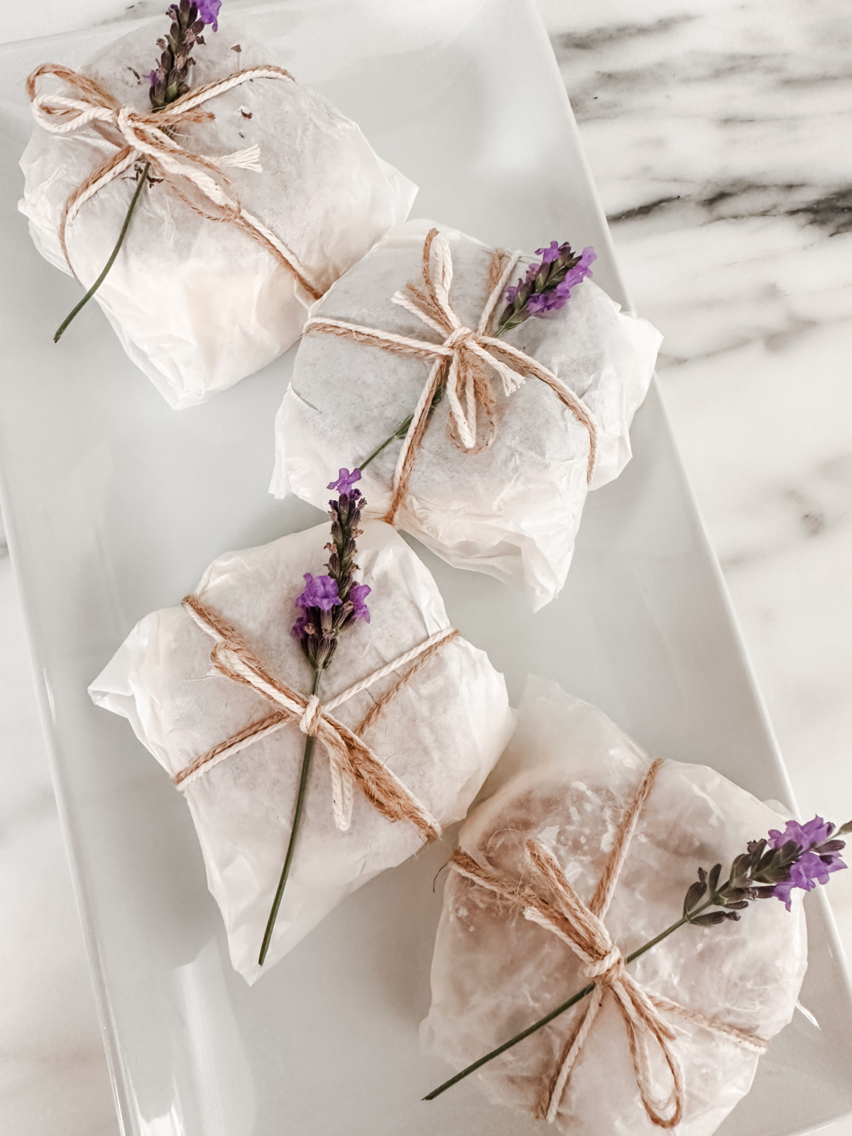 Homemade ice cream sandwiches wrapped in parchment and twine, on a platter.