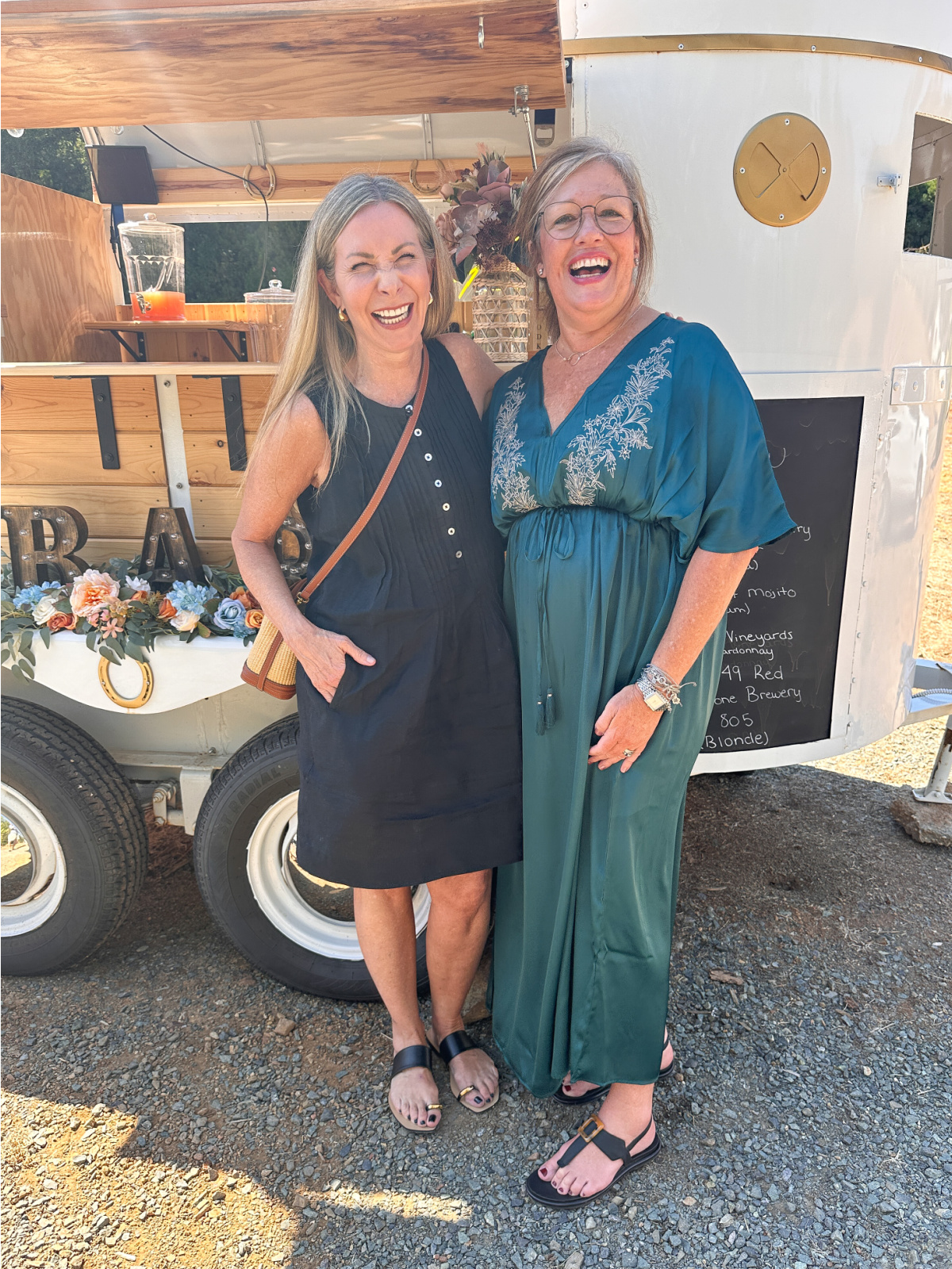 Two woman standing front of mobile bar laughing.