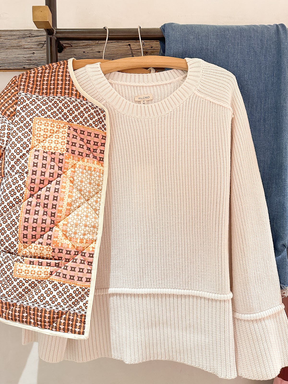 Quilted jacket, ivory sweater and jeans hanging in dressing room at Anthropology.