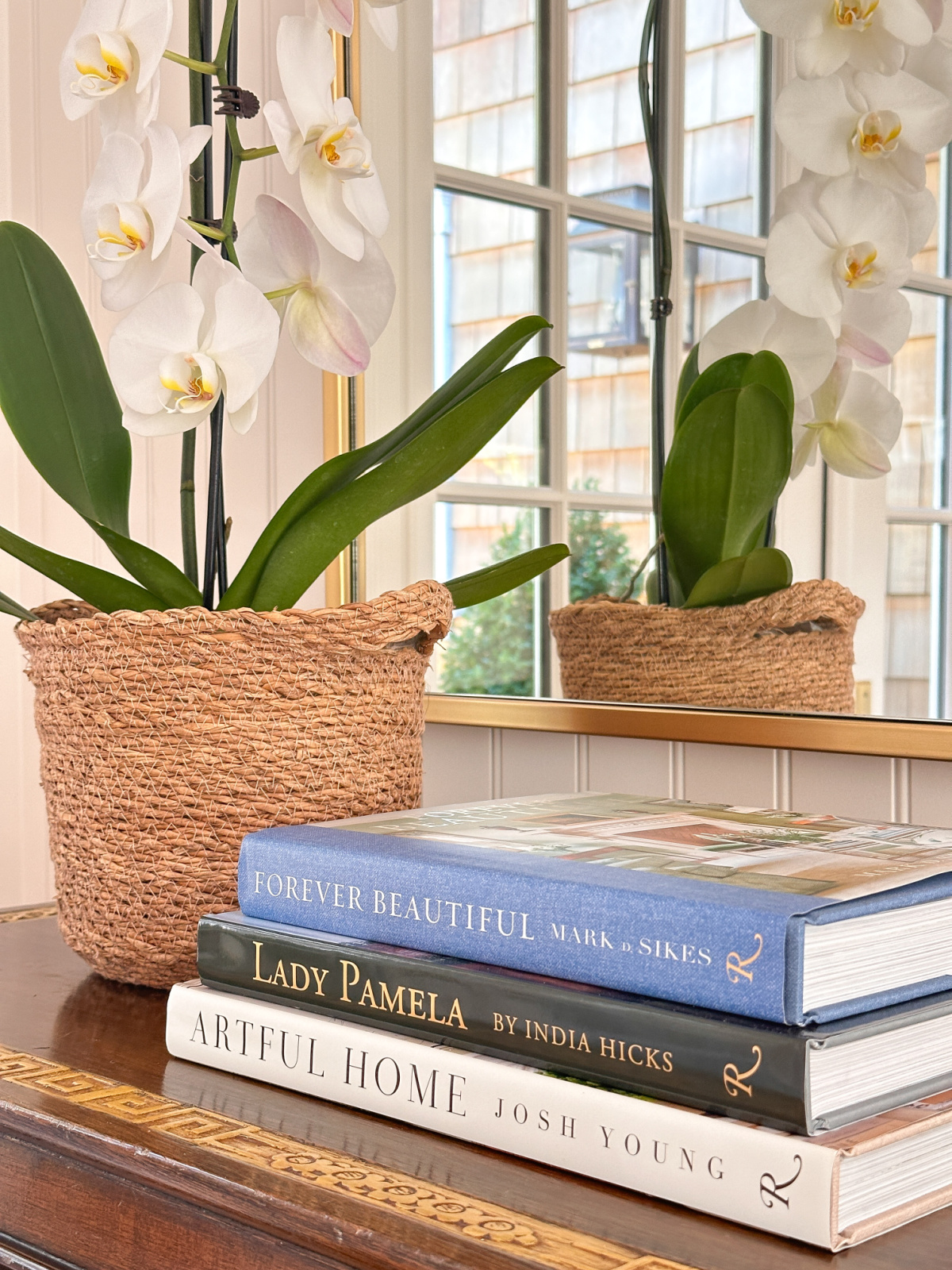 Stack of decor books next to orchid in basket.