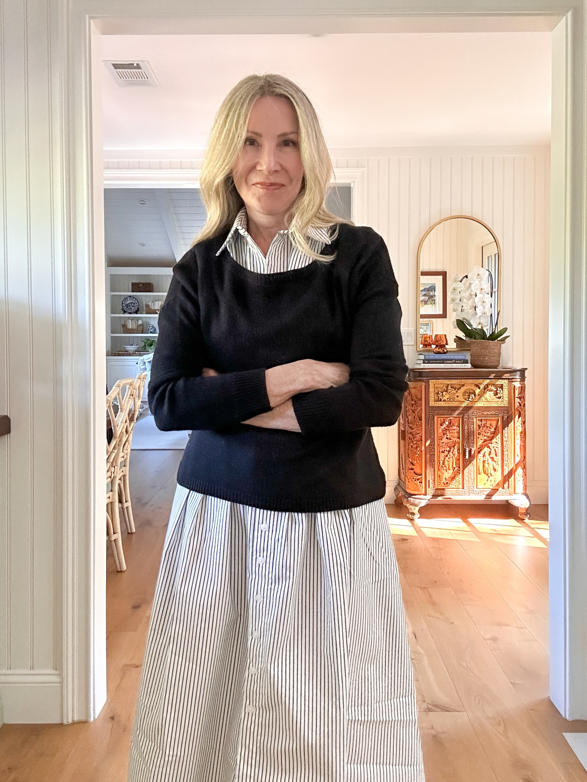 Woman wearing black and white stripe Anthropologie dress and cropped black sweater.