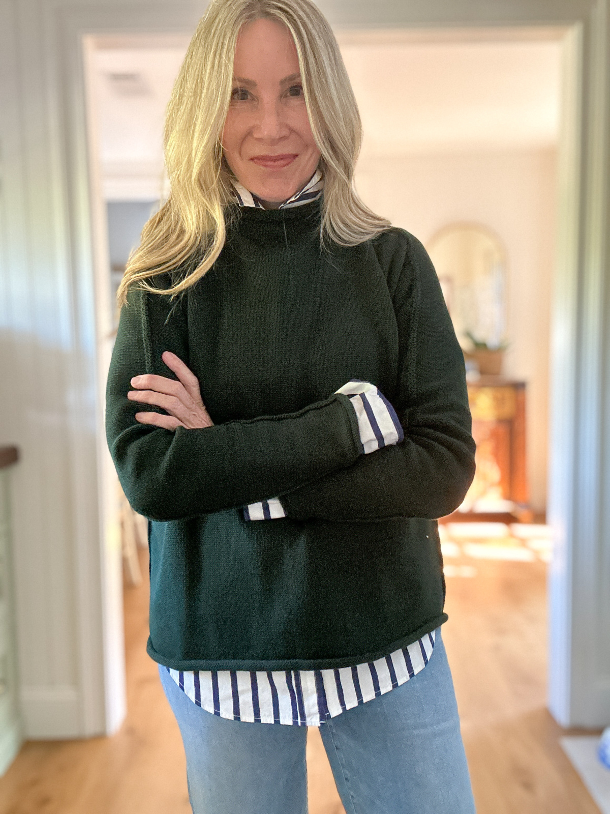Woman wearing striped shirt and dark green sweater.