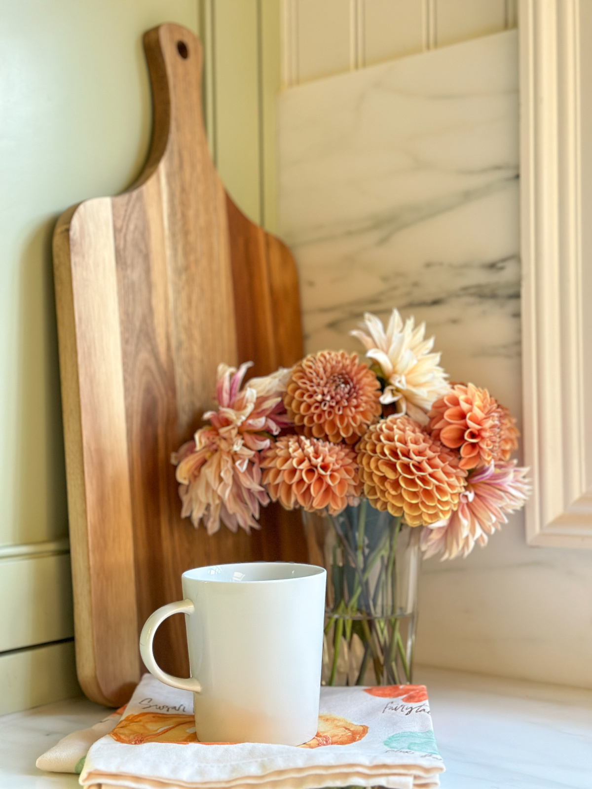 Glass of dahlias on kitchen counter.