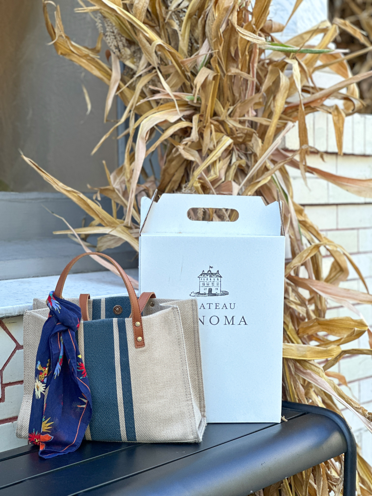 Striped tote on bench next to champagne box in Sonoma.
