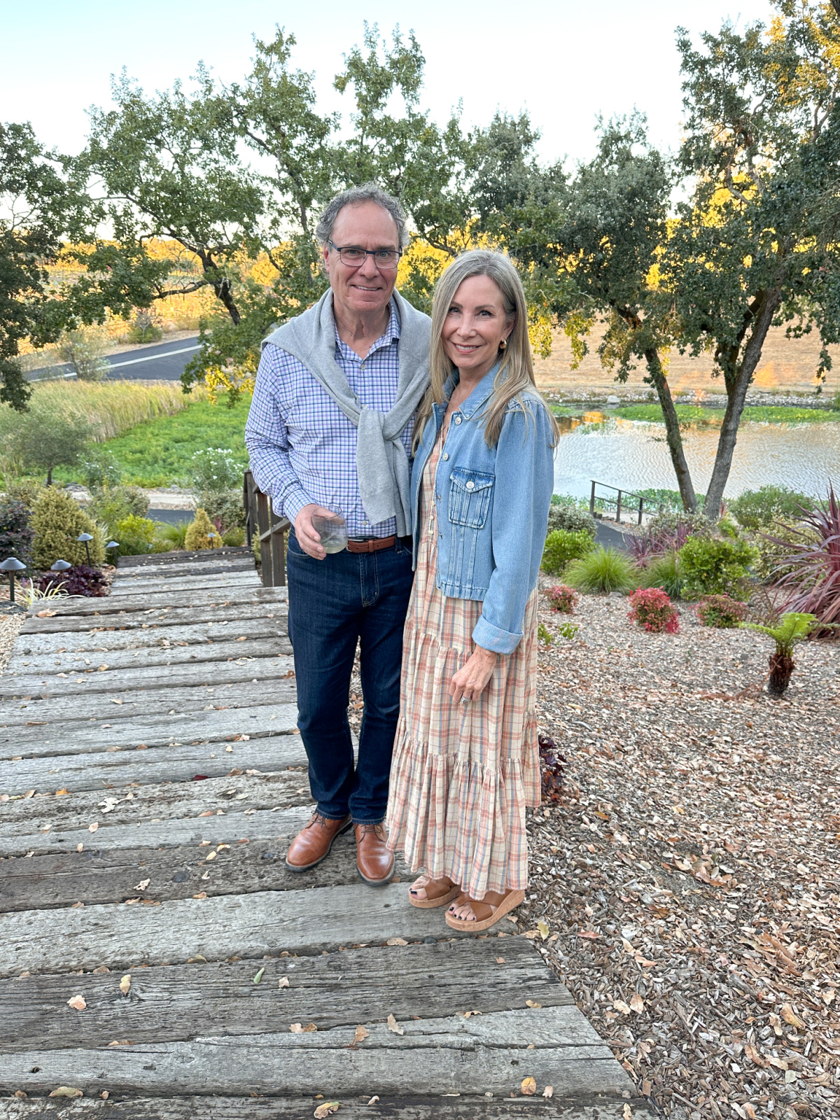 Couple standing on gravel path in front of lake.