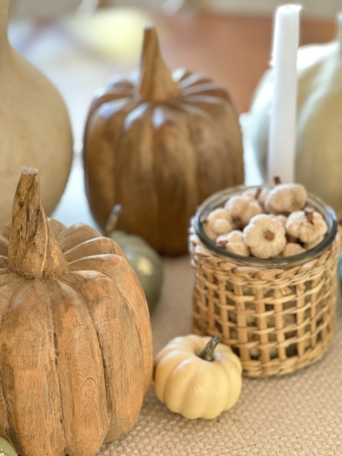 Natural pumpkin pods in rattan wrapped vase on fall table setting.