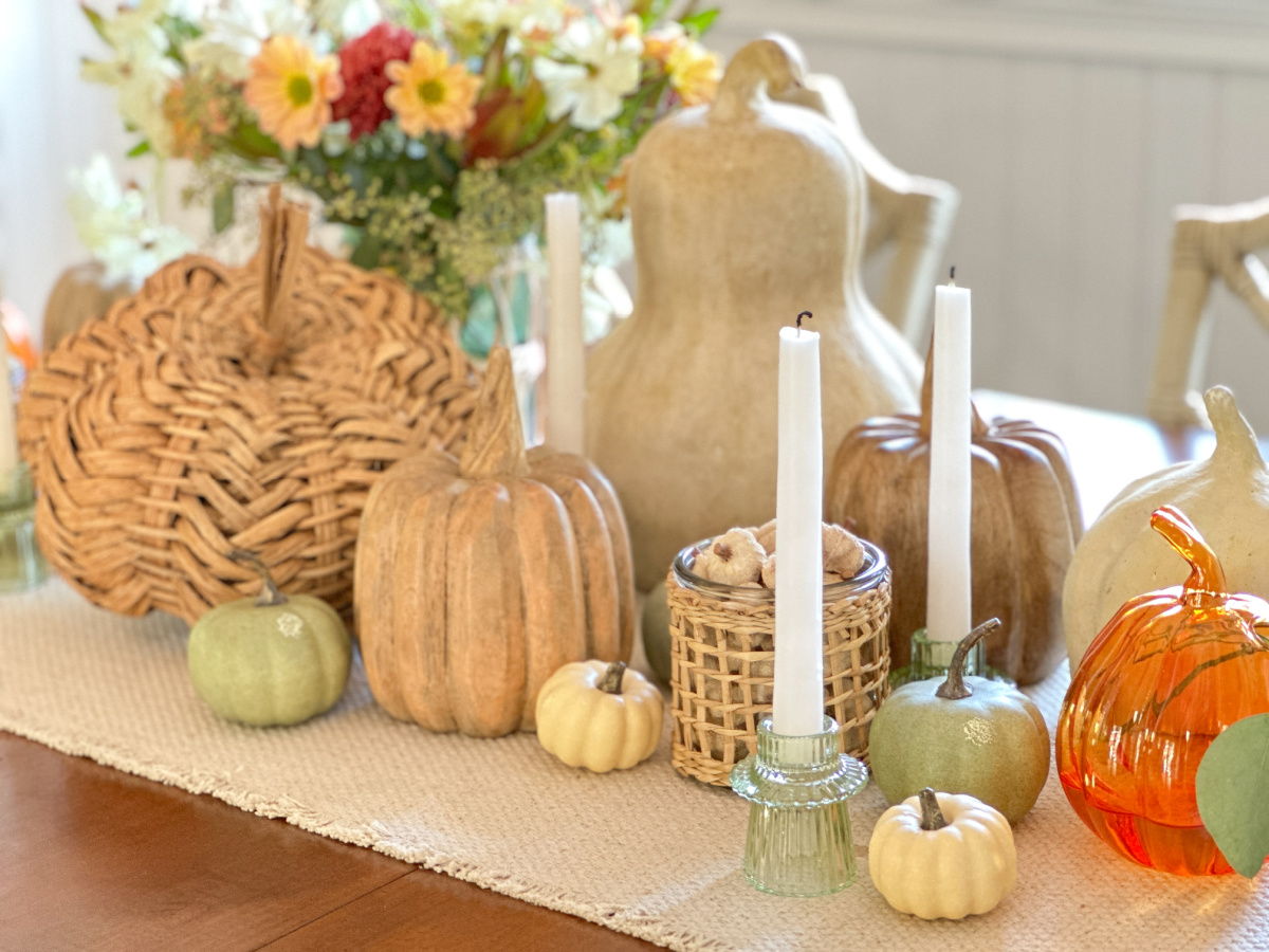 Fall table centerpiece with pumpkins, gourds and candles.