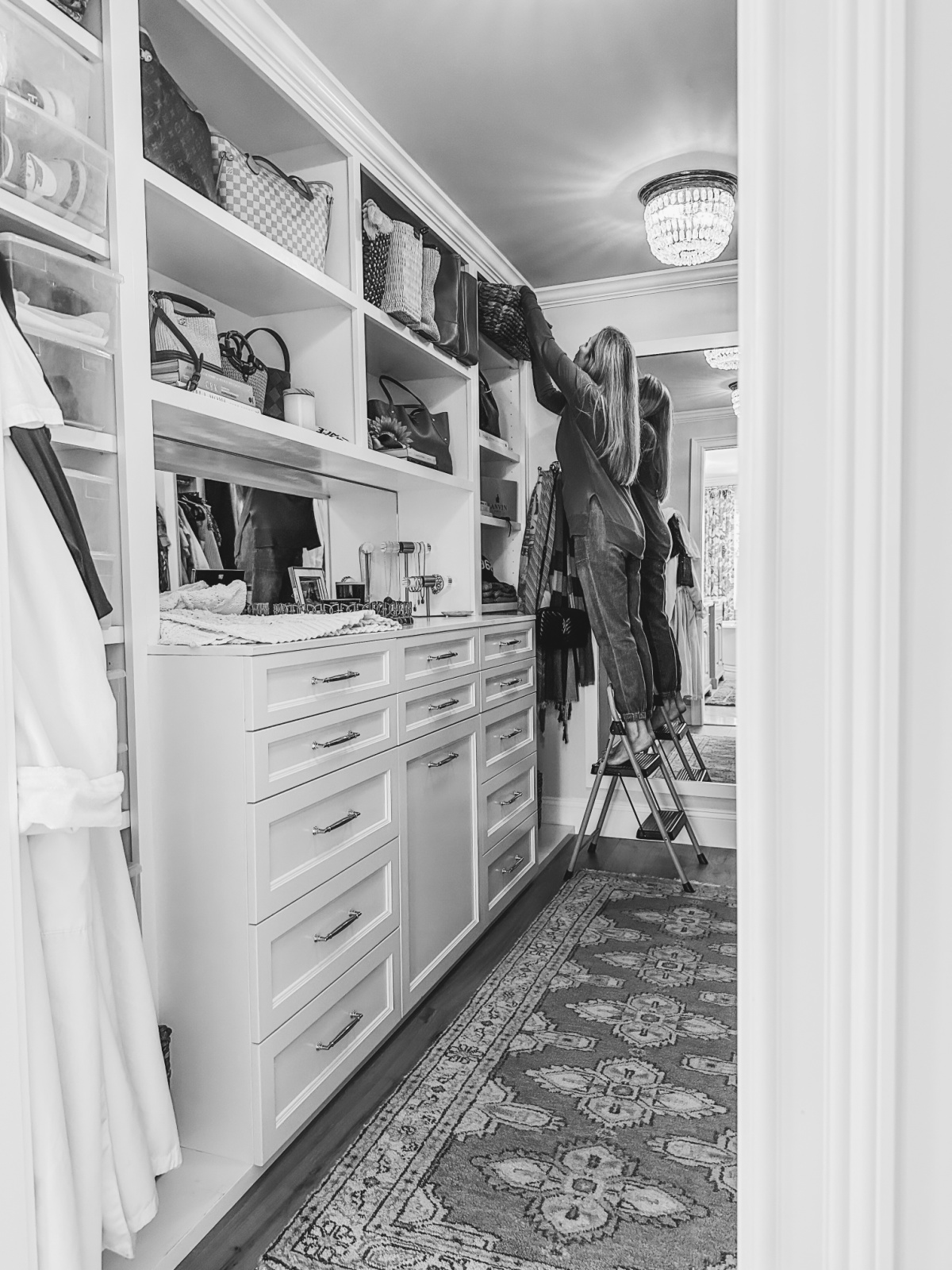 Woman on step ladder cleaning walk in closet.