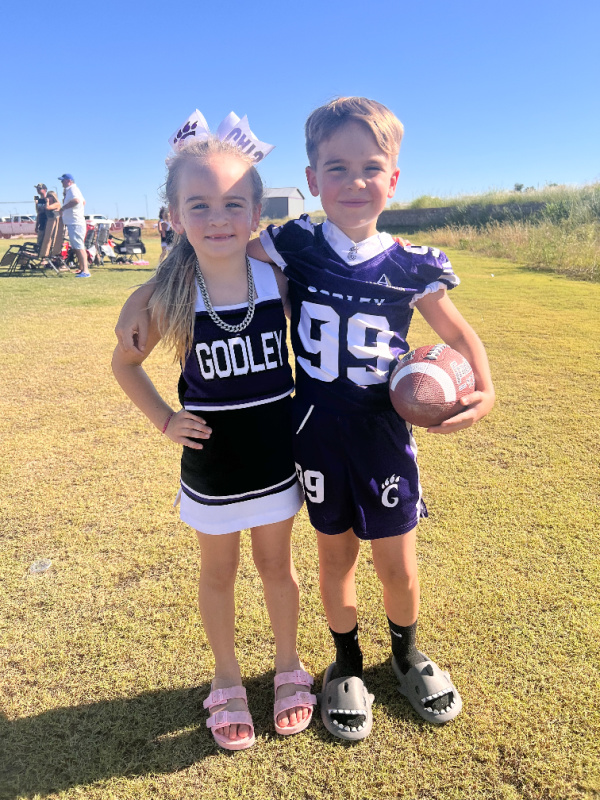 Young cheerleader and football player on the sidelines.