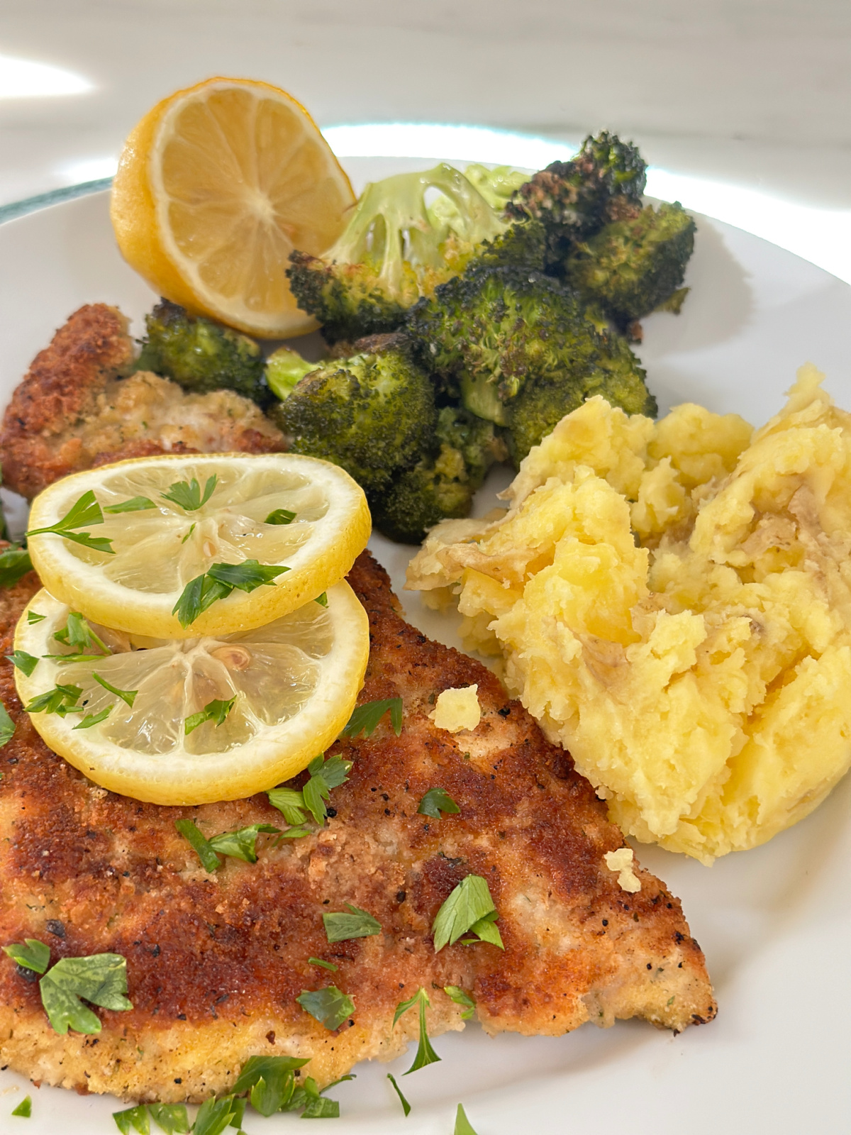 Plate of Ina Garten's chicken piccata, mashed potatoes and roast broccoli.