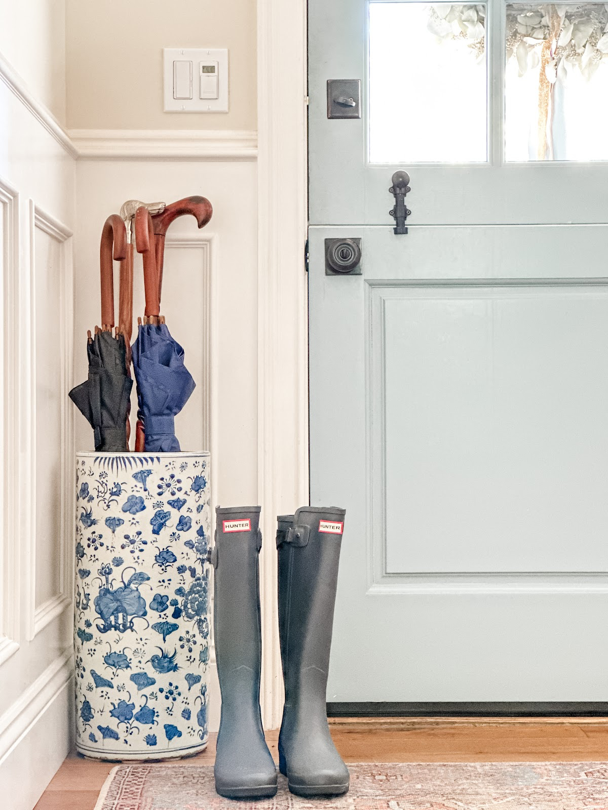 Blue Hunter Rain boots sitting next to blue Dutch Door.
