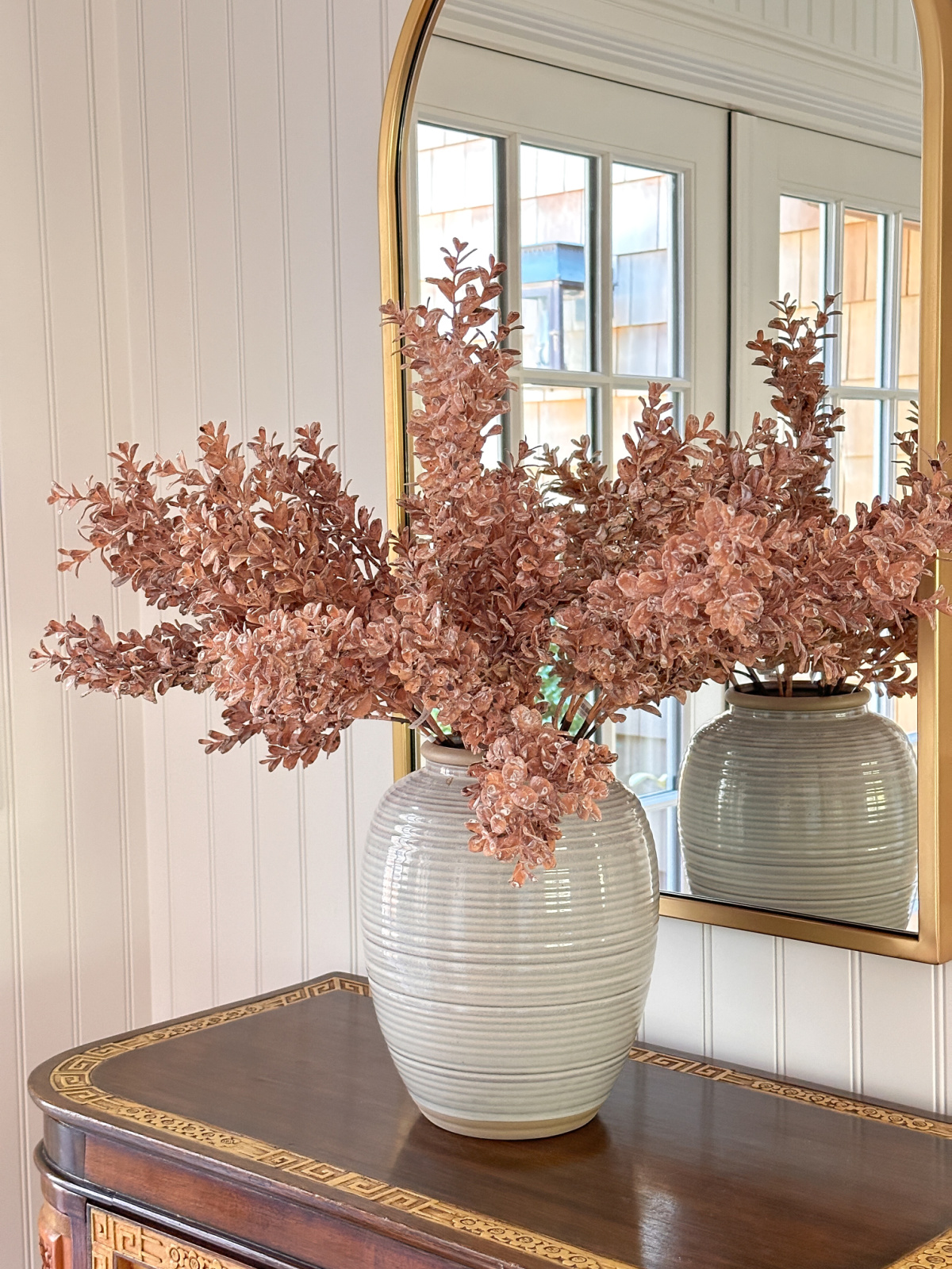 Faux dusty rose stems in large vase on Asian chest.