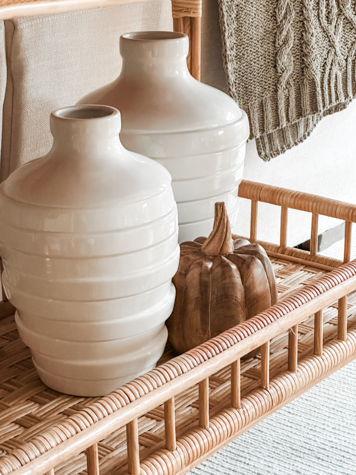 Wood pumpkin next to ivory vases.