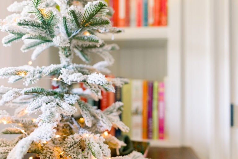 flocked countertop Christmas tree in front of colorful cookbooks.