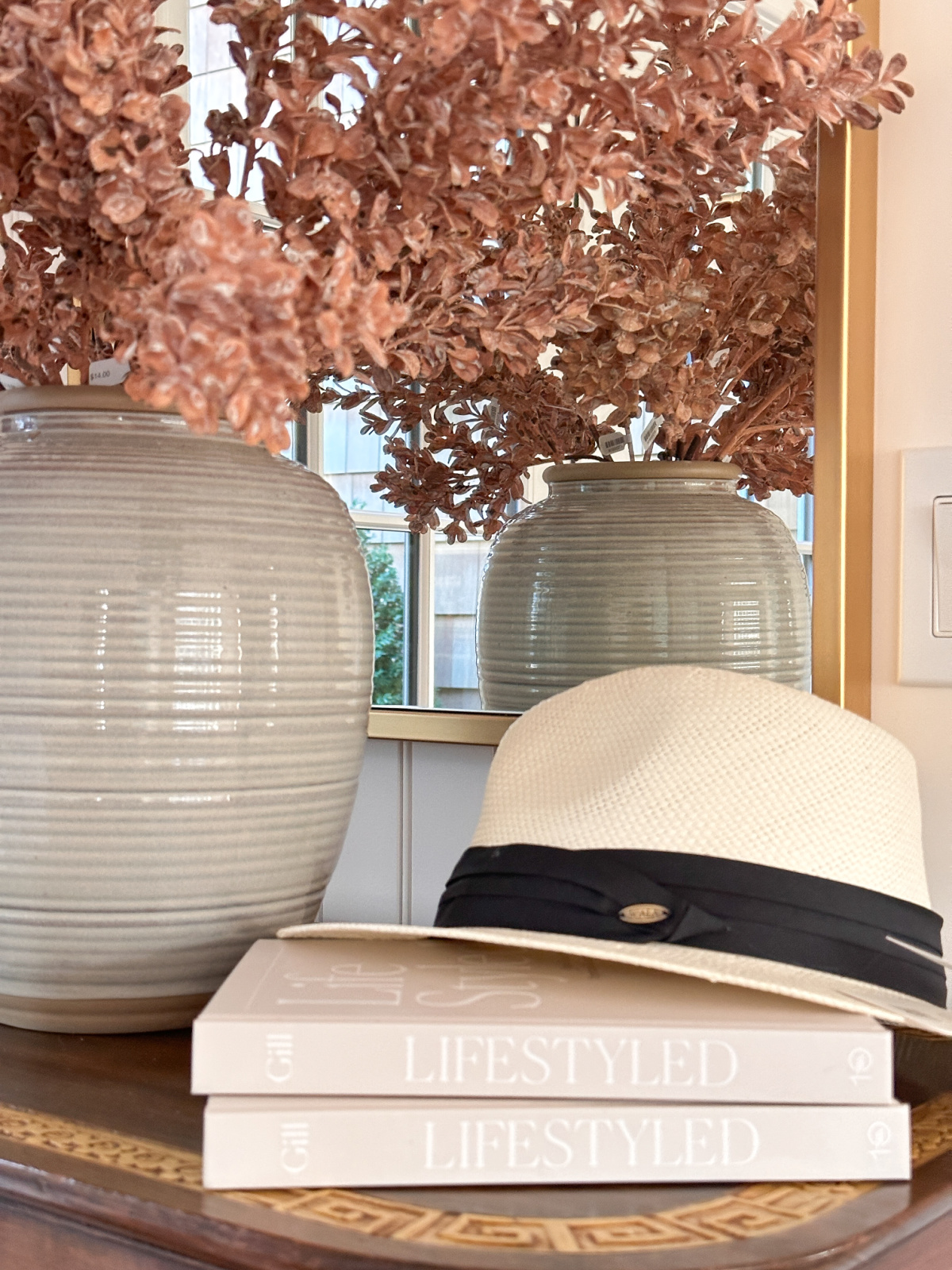 Life Styled books with hat on top net to vase of stems.