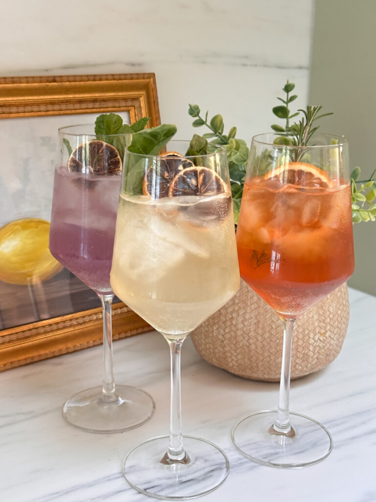 Three wine glasses of Saint Spritzes on kitchen counter.