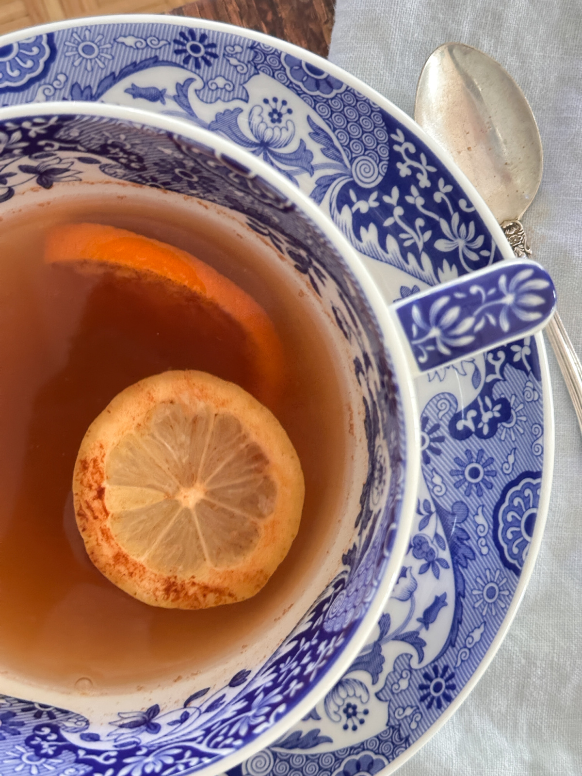 Overhead shot of citrus, honey and cinnamon tea in cup and saucer.