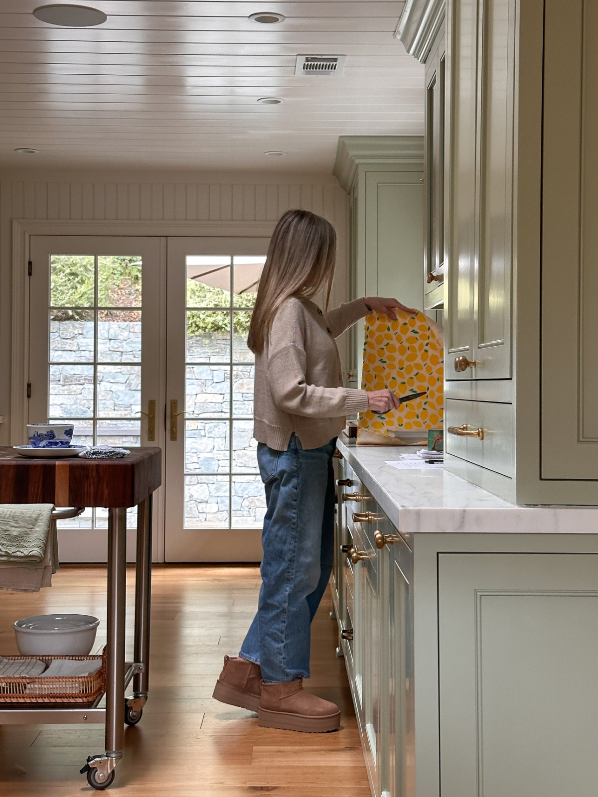 Woman gift wrapping books in a green kitchen.