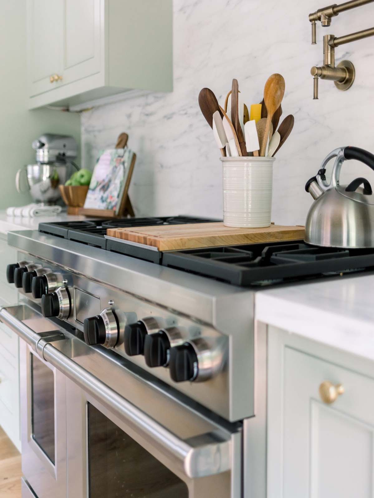 Kitchen counter including range, tea kettle, utensil crock and Kitchen Aid mixer.