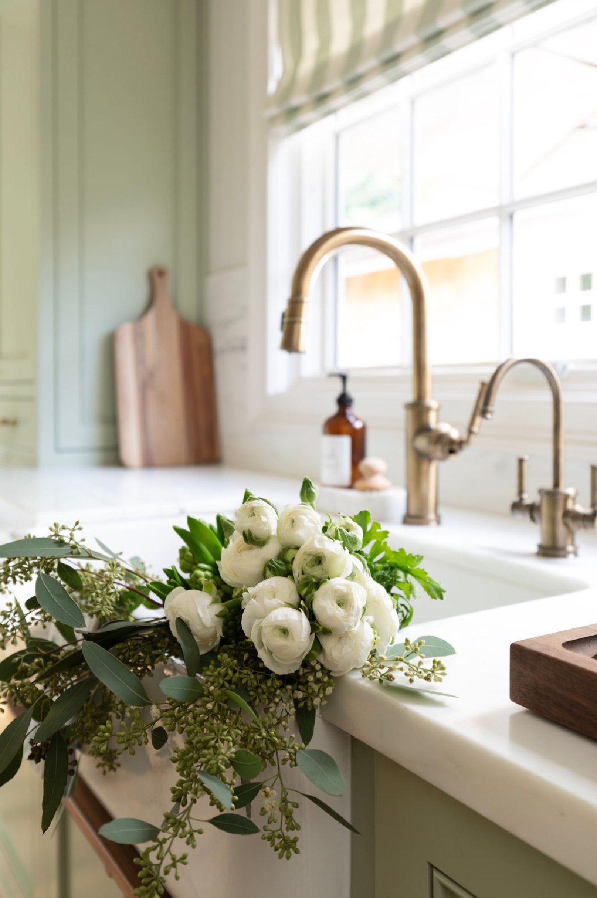 Green kitchen with white flowers in sink.