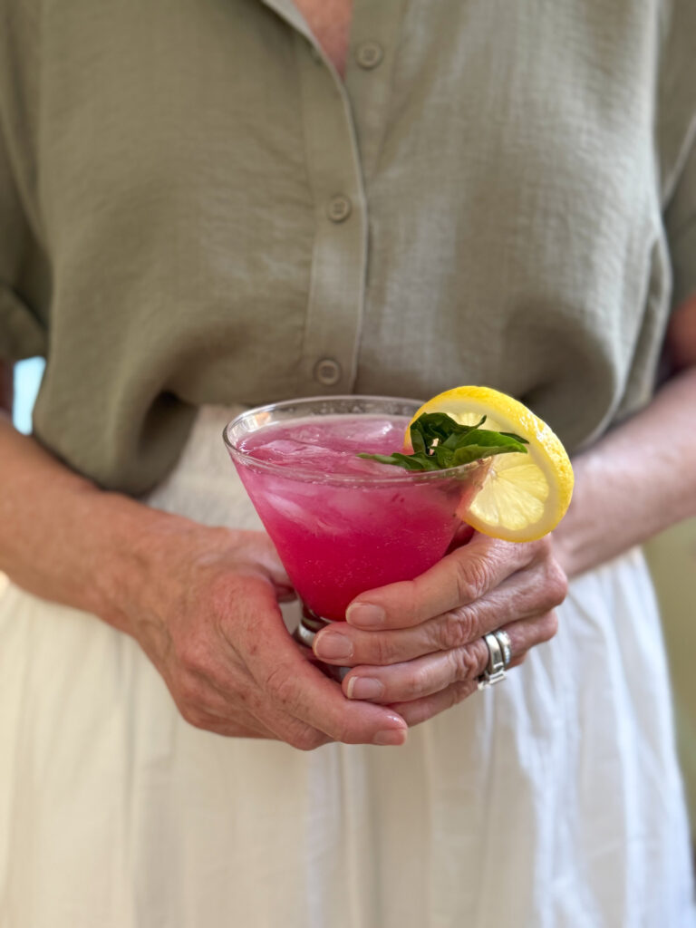 Woman holding Boozy Blueberry Basil Lemonade cocktail.