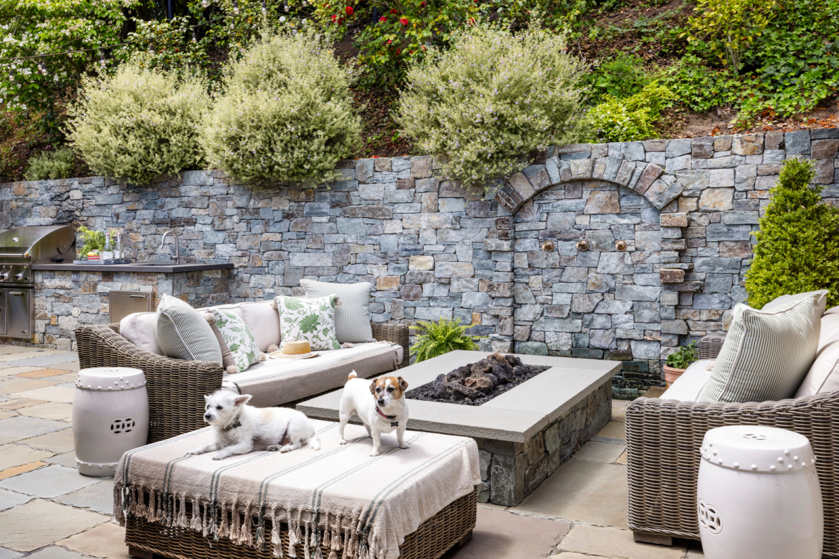 Dogs sitting on outdoor patio ottoman.