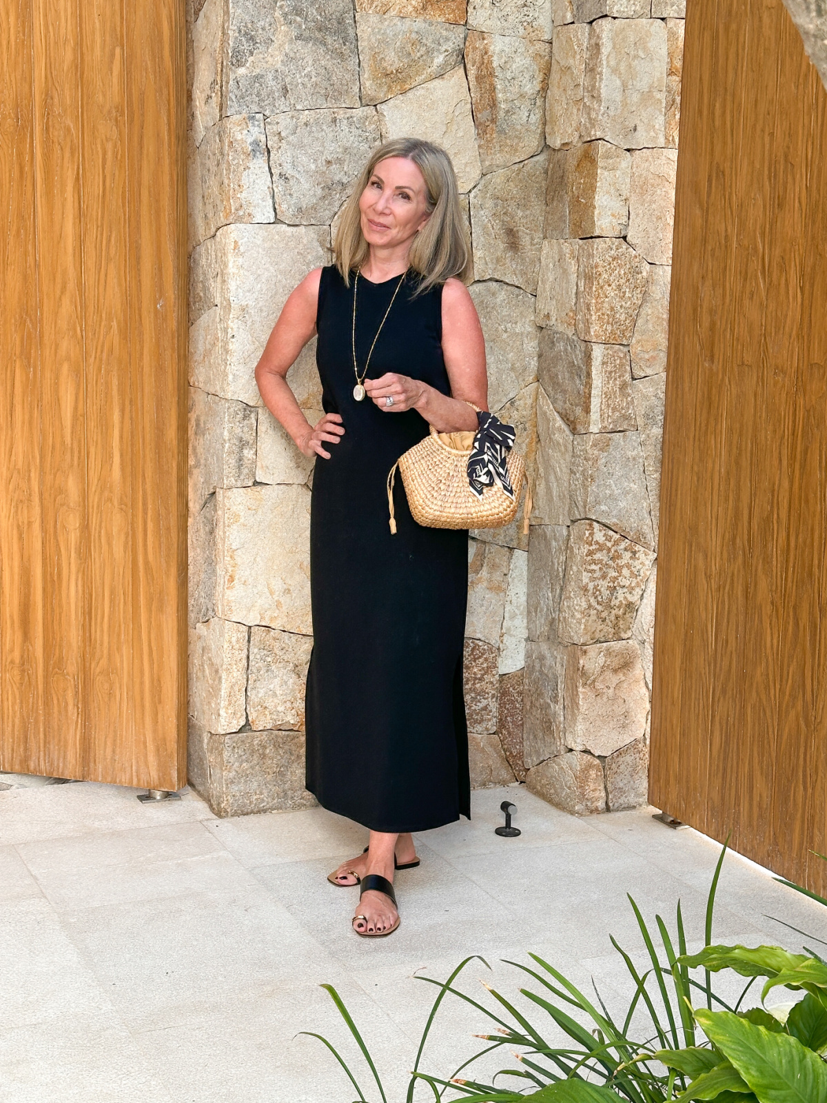 Woman wearing black Tuckernuck black maxi dress with straw tote in Cabo.