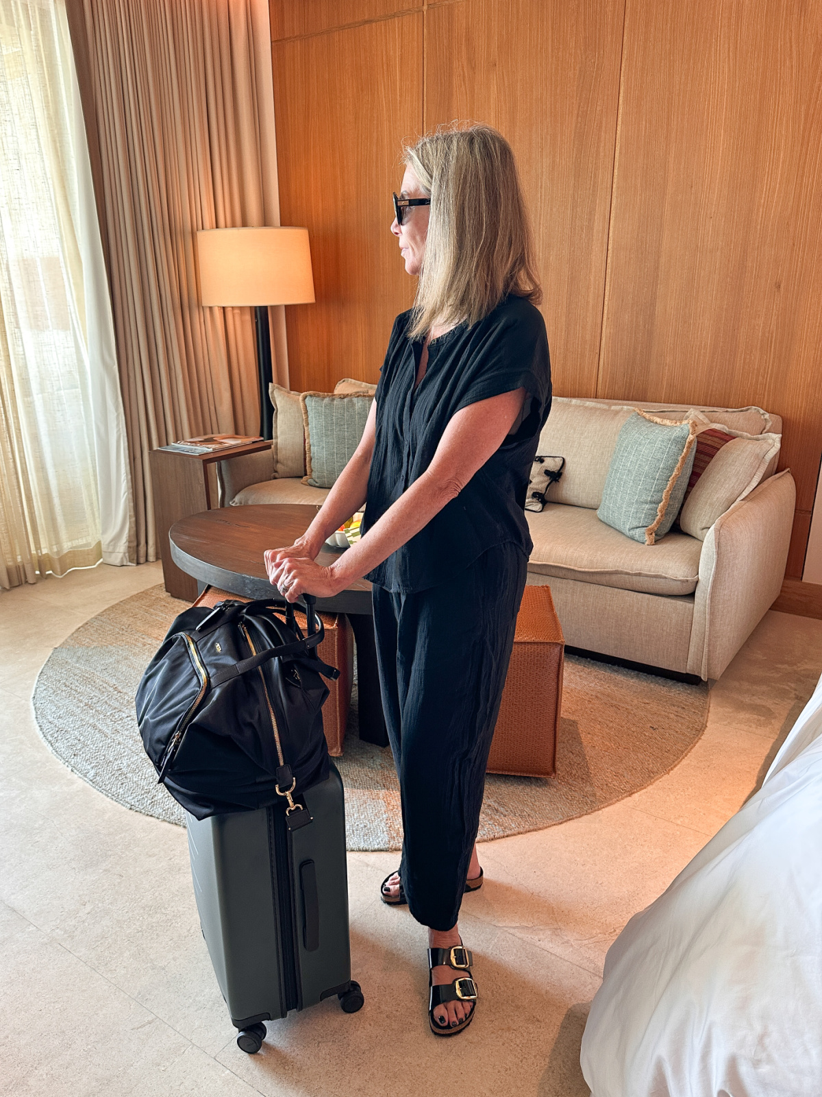 Woman wearing Gap Gauze Set holding Quince and Tumi luggage.