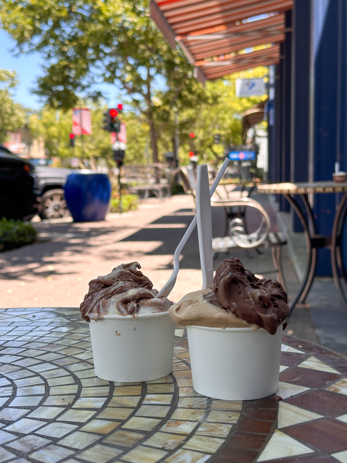 Two cups of gelato at sidewalk cafe.