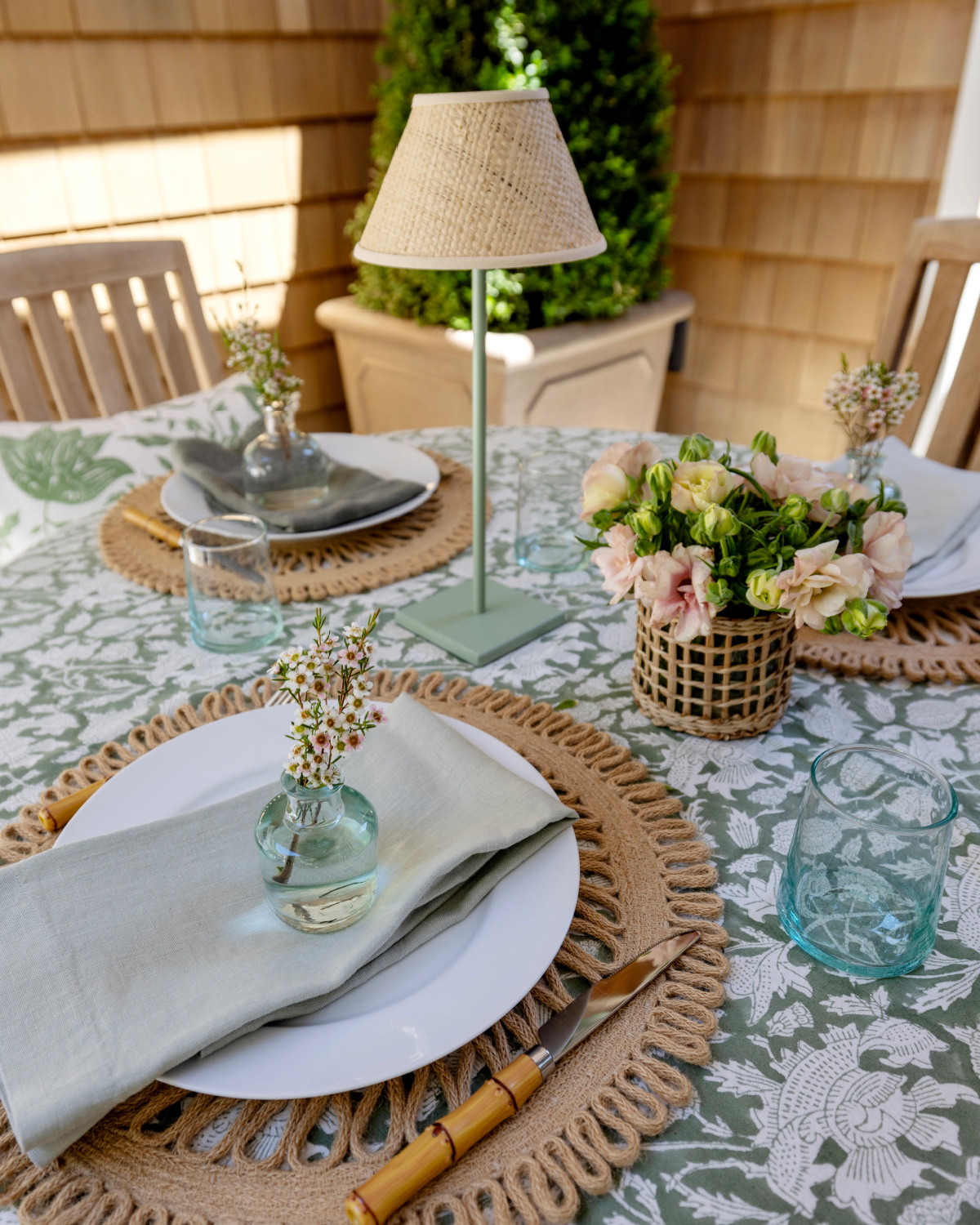 Outdoor table setting in green, white and raffia.