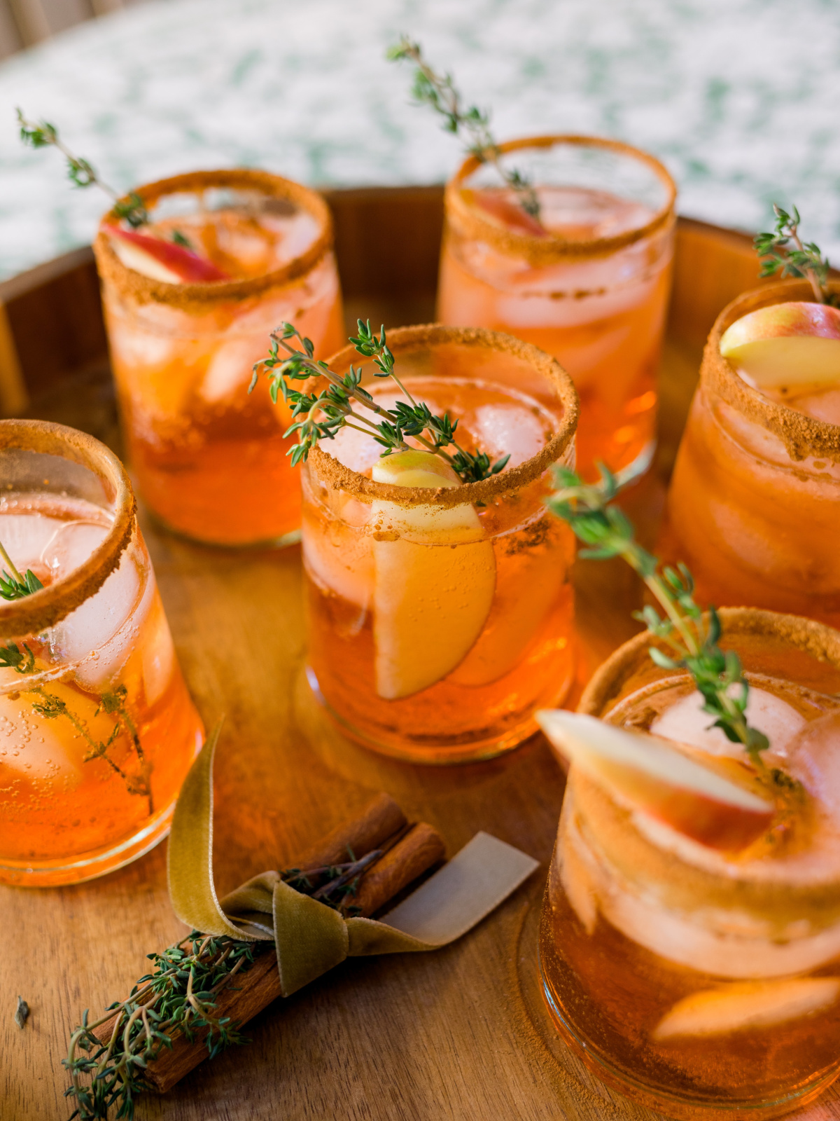 Apple cider Aperol spritz drinks on wooden tray.