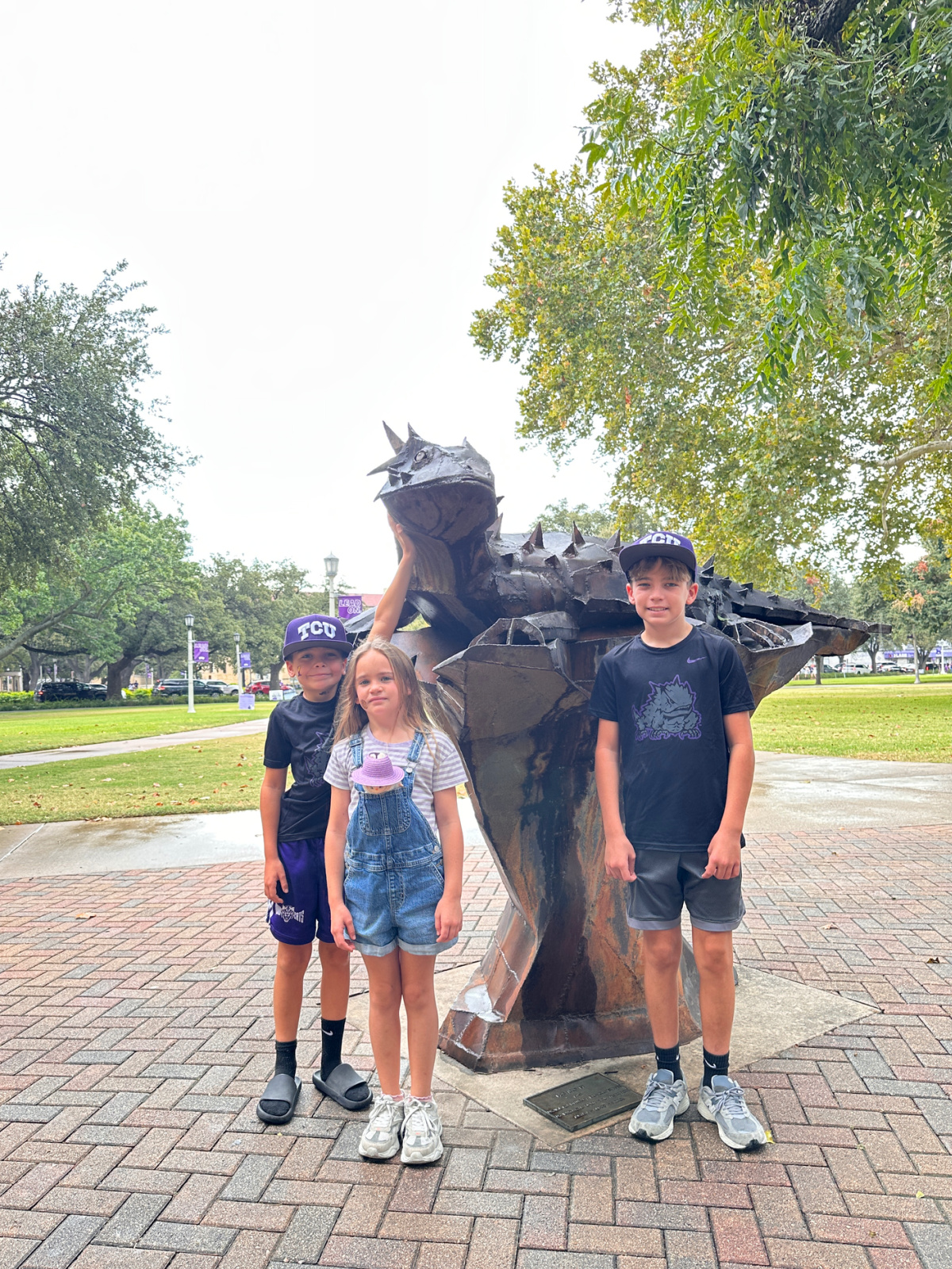 Three kids rubbing Superfrog for luck before TCU Baylor game.