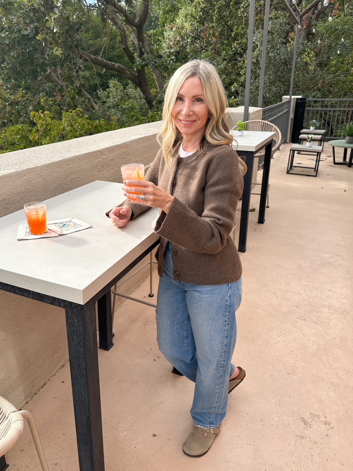 Woman holding spritzer on patio wearing Quince Cashmere structured cardigan.