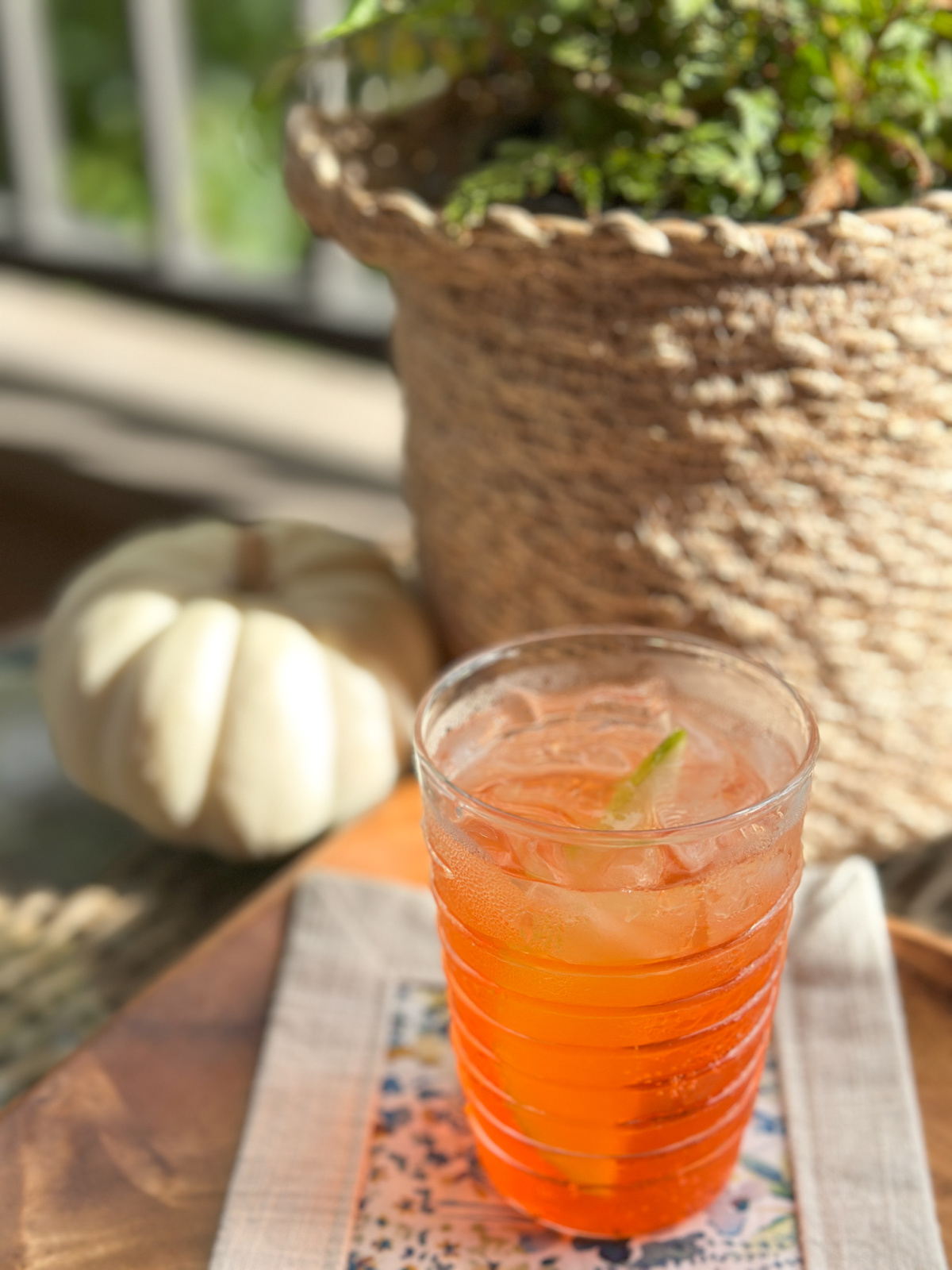 autumn spritzer on patio table next to small pumpkin and fern.