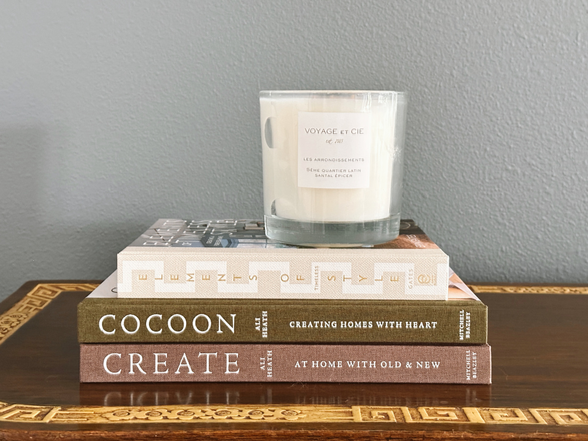 Stack of decor books and candle on Asian console table.
