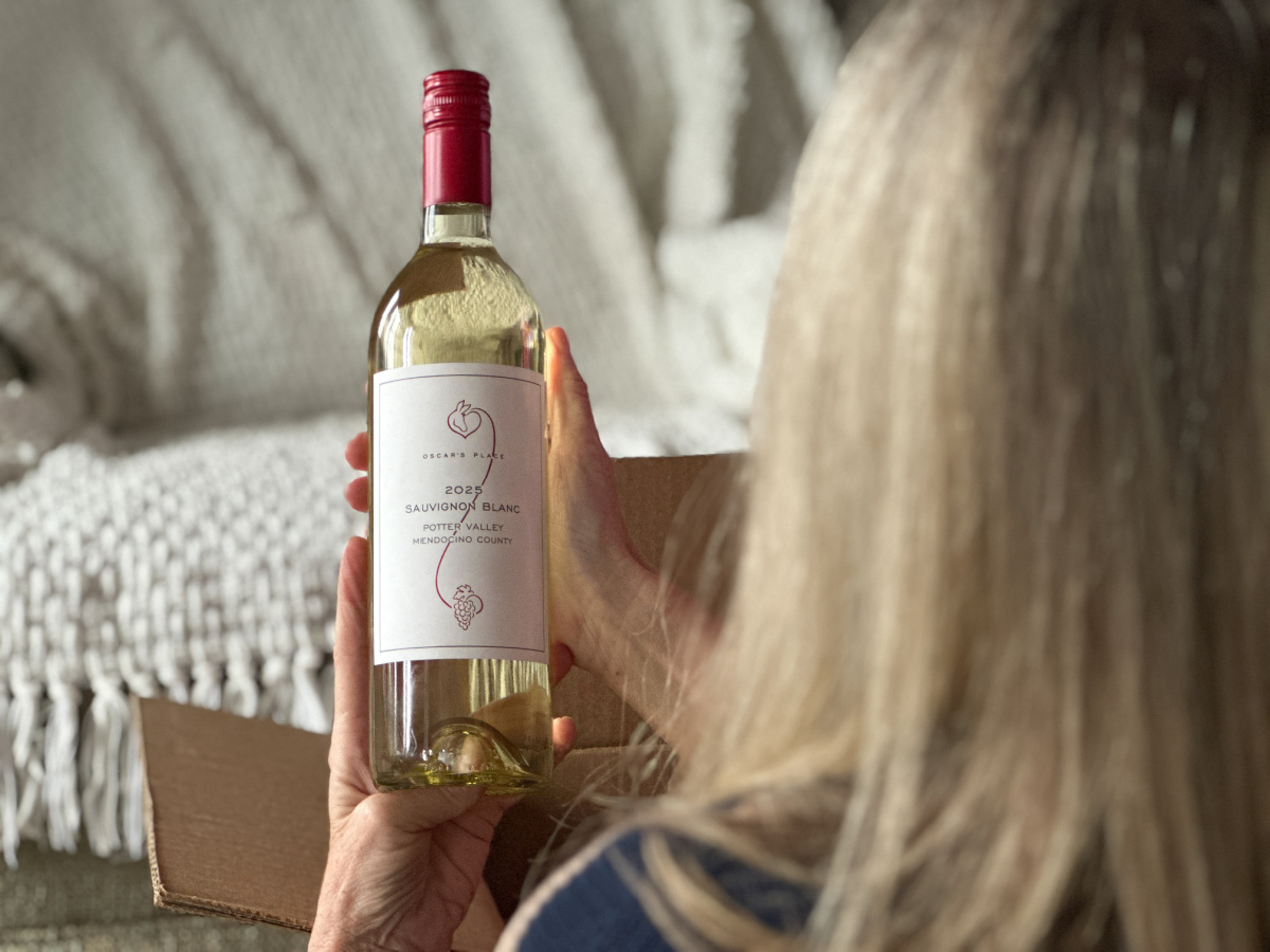 Woman holding bottle of Oscar's Place Sauvignon Blanc.